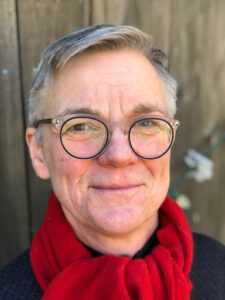 Headshot of Dr. Ann Gordon. She is smiling and wearing a bright red scarf.